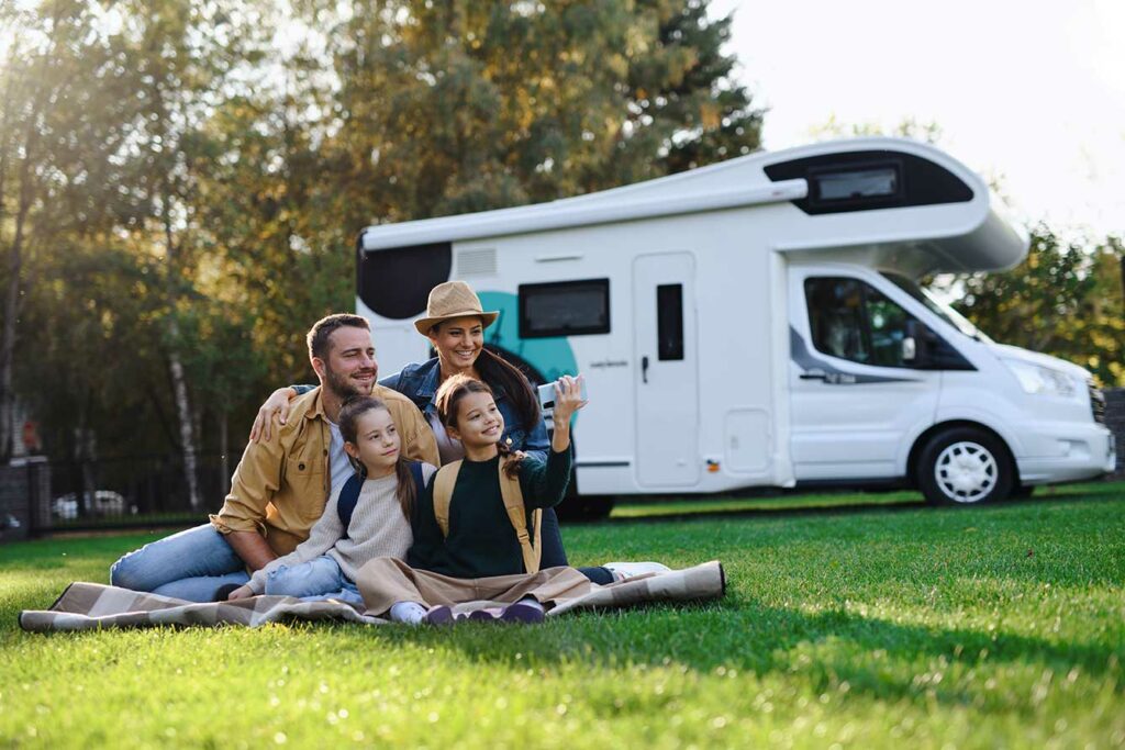 Famille avec enfants prenant une photo devant leur camping-car personnel pendant des vacances