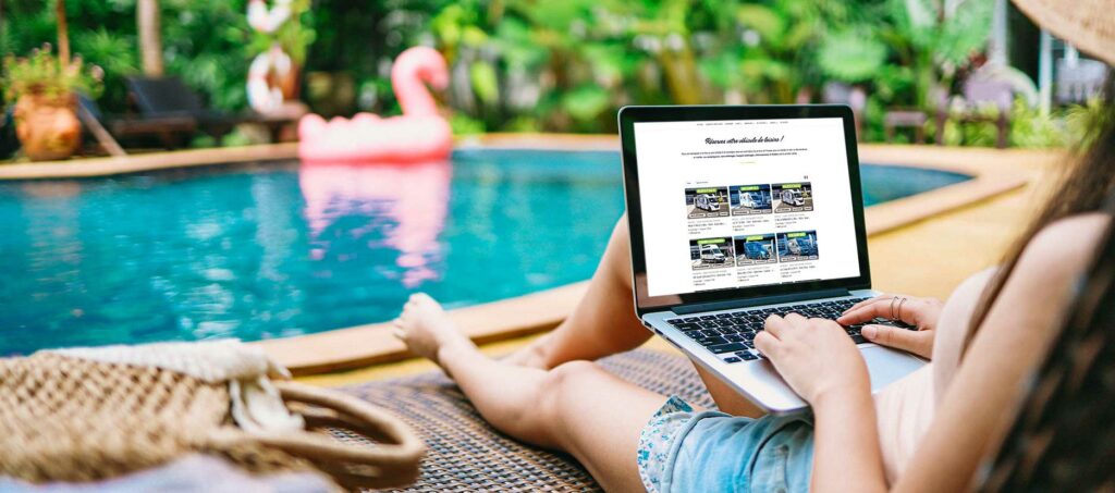 Jeune femme réservant un camping-car sur le site de Roots Evasion prés d’une piscine